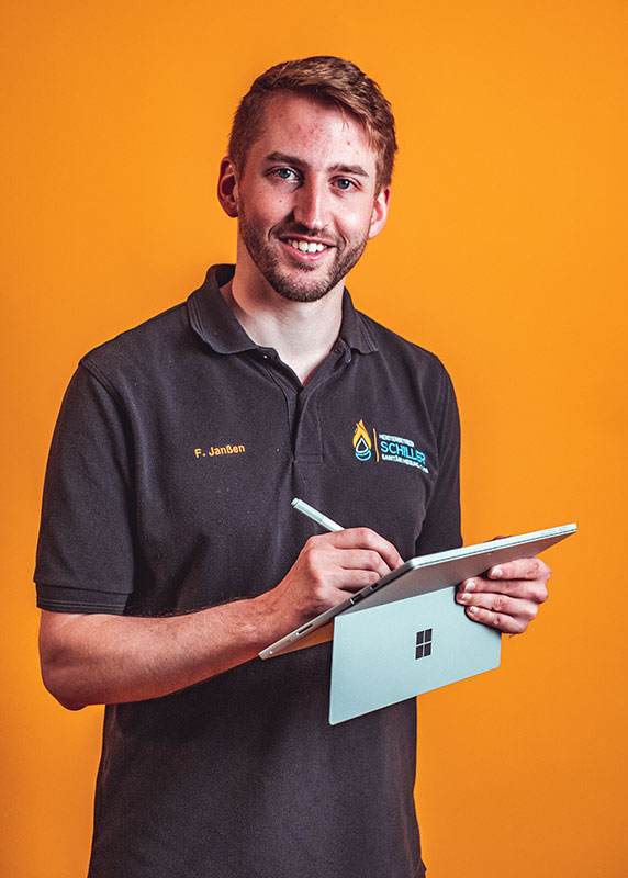 Mitarbeitende des Betriebs posieren vor orangem Hintergrund mit typischen Arbeitsmitteln wie Laptop, Tablet, Telefon oder Werkzeug.